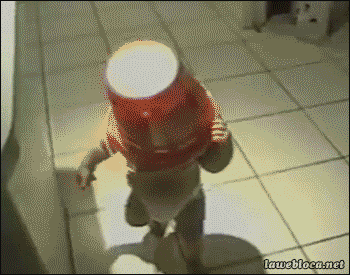 Мальчик пытается пройти в дверной проем с ведром на голове